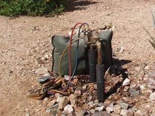 A bag with a hose attached to it is sitting on a pile of rocks.