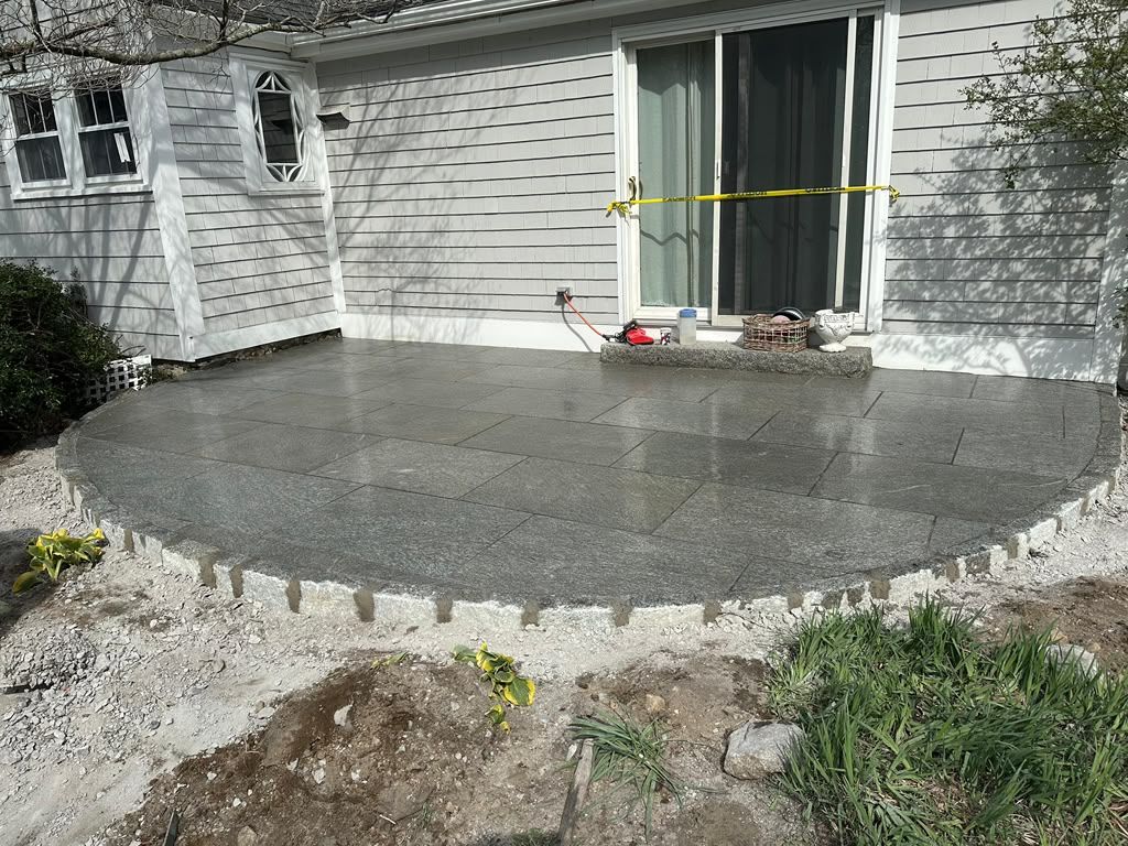Freshly poured concrete patio in front of a house, with sliding glass door and yellow caution tape