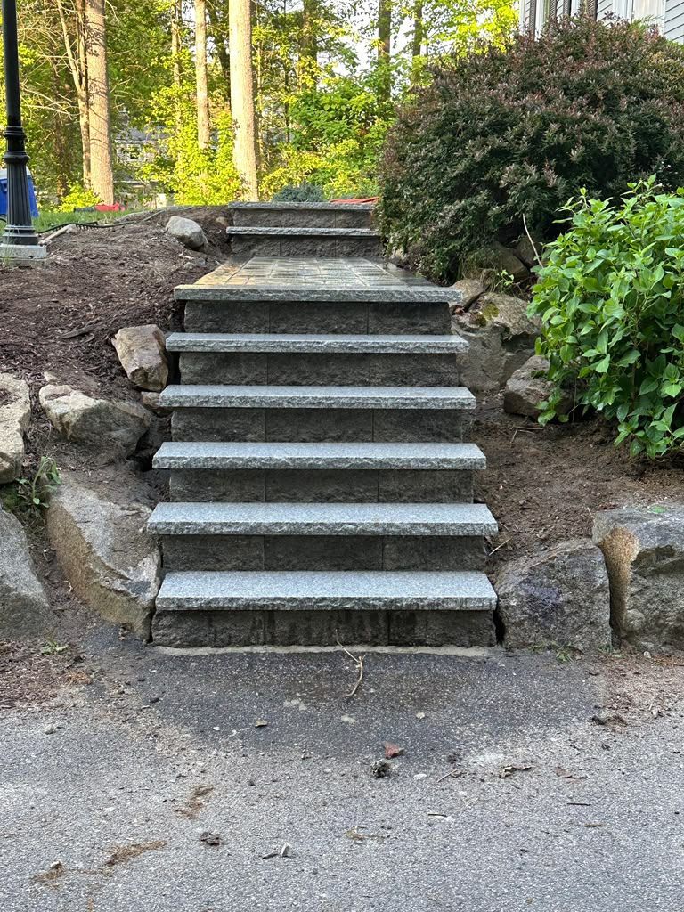 Stone steps leading up a landscaped garden path, bordered by rocks and shrubs