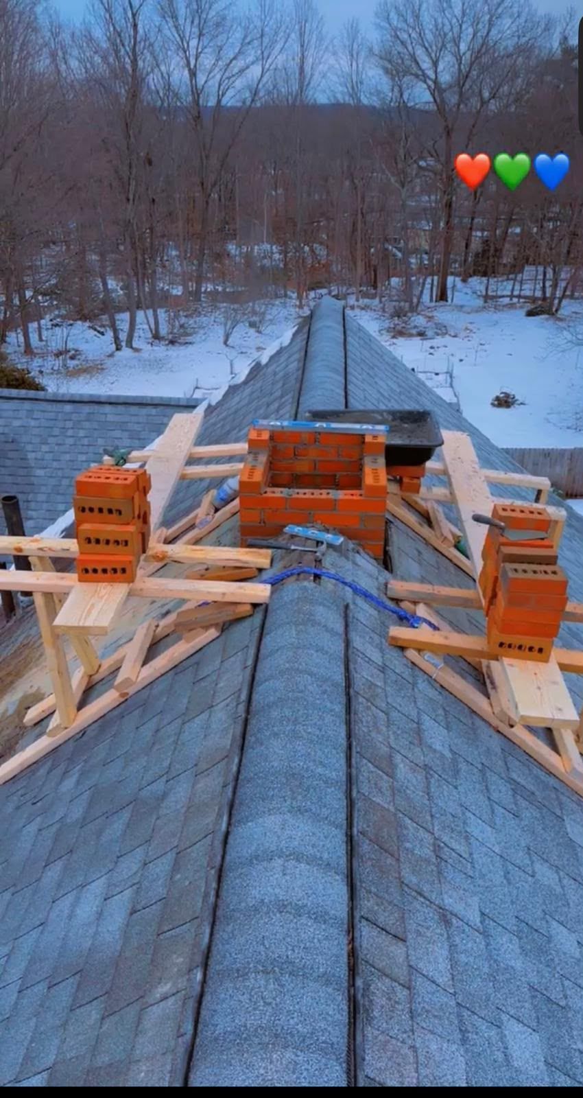 Wooden bridge under construction over a snowy creek, with orange safety barriers and materials on the deck