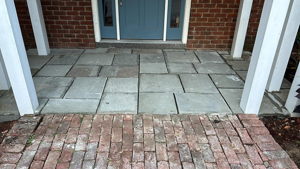 Brick and stone front porch with steps leading to a glass door