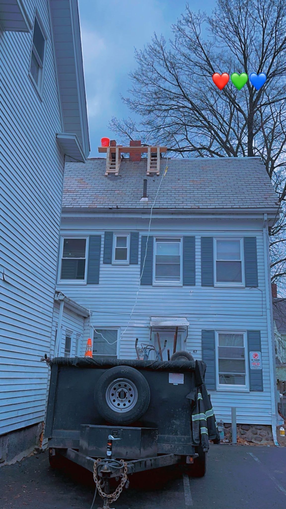 Two-story house with a chimney repair truck and a fenced driveway under a dusky sky