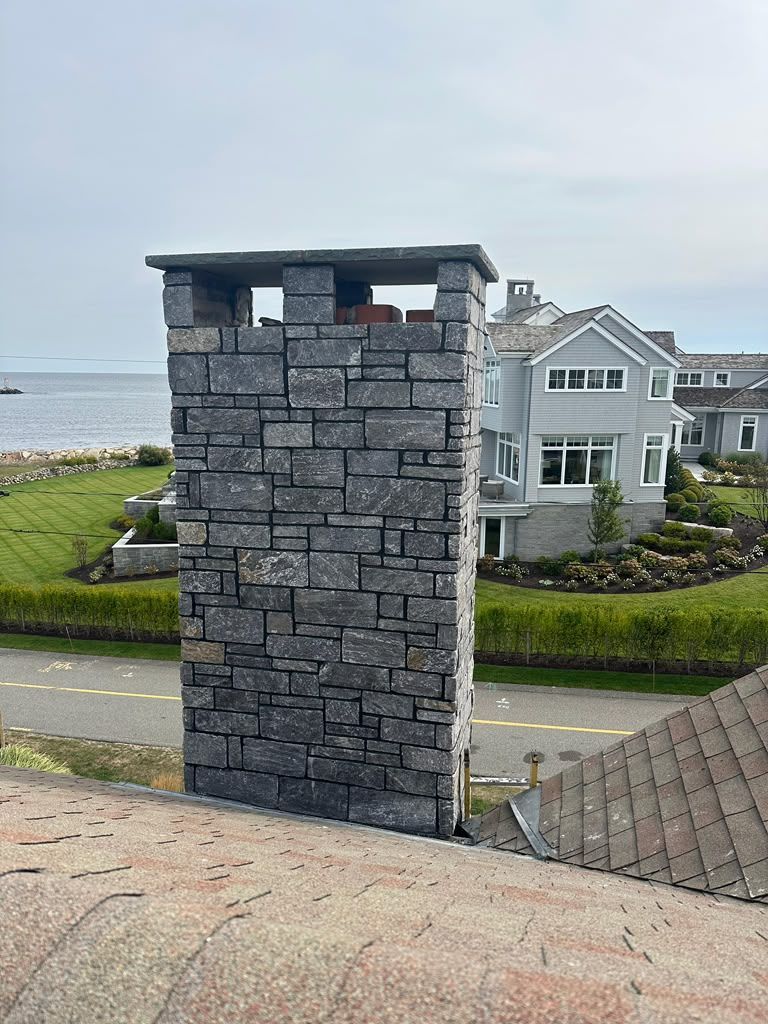 Stone pillar by a coastal road with houses and sea in the background