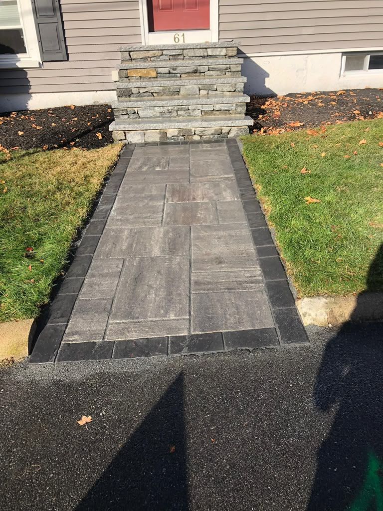 Front walkway with stone steps leading to a red front door, bordered by grass and mulch.