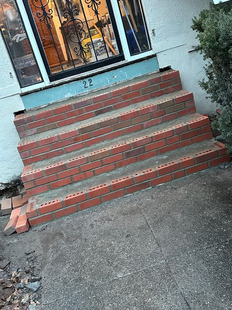 Brick steps leading to a house entrance with a metal door and windows above it