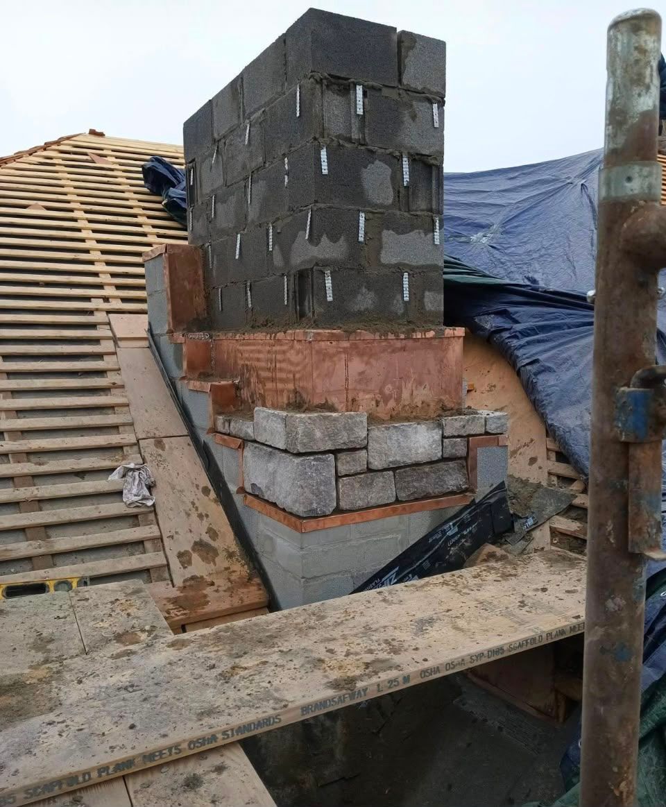Partially built brick wall with stacked cinder blocks and wooden scaffolding at a construction site