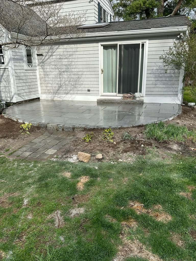 Back patio with concrete slab and sliding glass door on a stone and vinyl house exterior