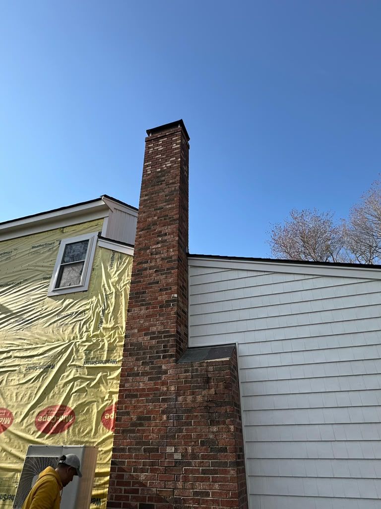 Brick chimney on a house exterior against a blue sky