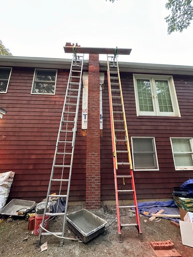 Two ladders leaning against a brown house under repair, with a roof platform and debris on the ground.
