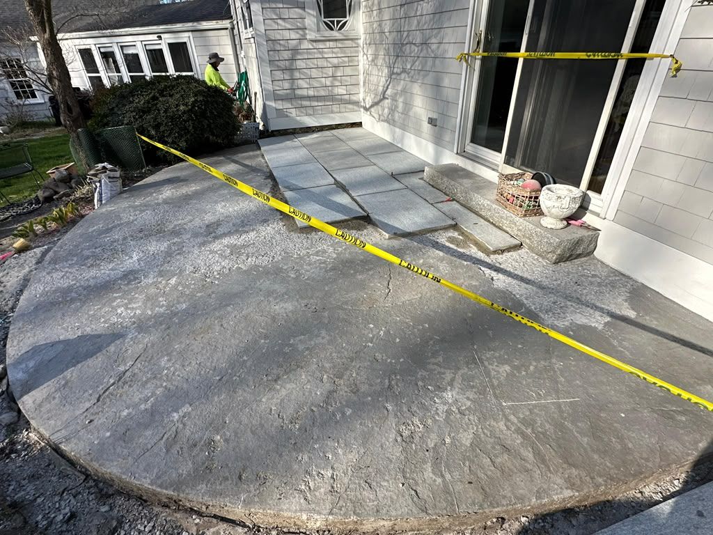 Concrete front porch with yellow caution tape blocking steps and entrance, near a house door and bush