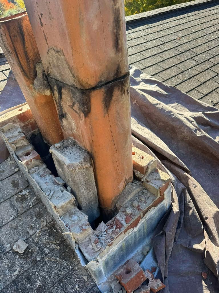 Damaged wooden post with a cracked concrete base on a rooftop deck