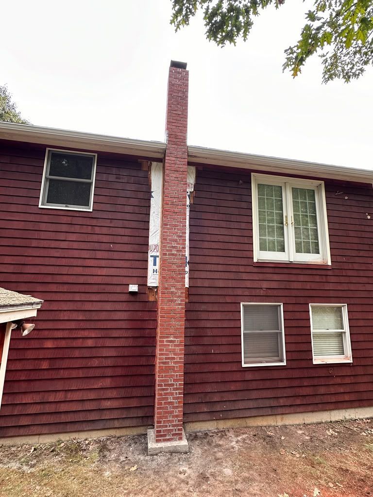 Red house exterior with white-trimmed windows and a brick chimney in the center