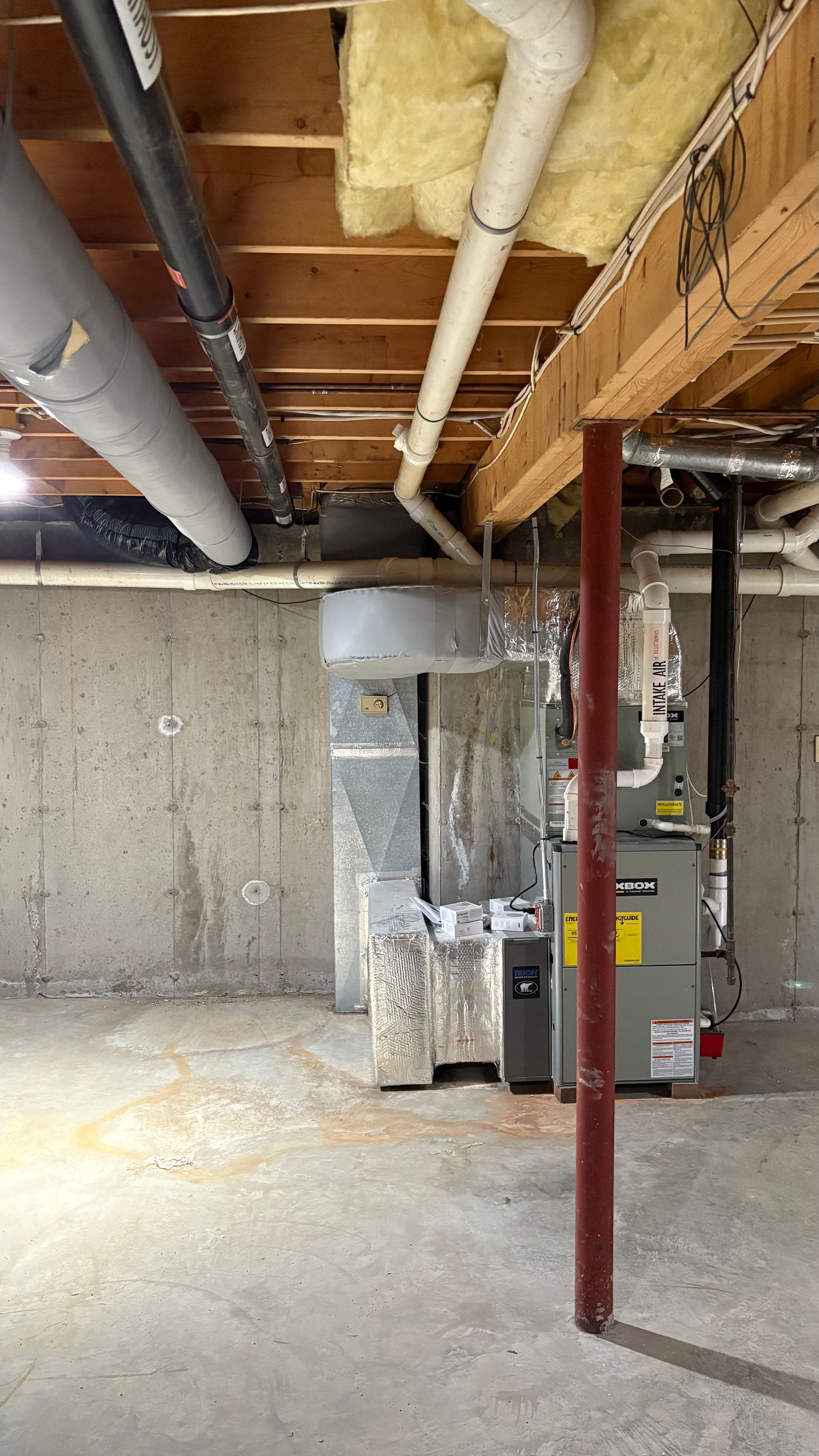 Basement with furnace, ductwork, pipes, support beam. Concrete walls and floor. Beige, grey, and white tones.