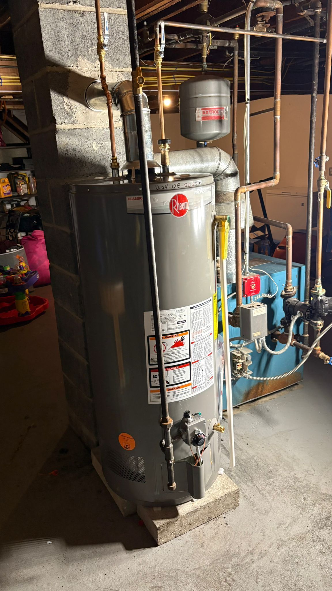 A water heater, pipes, and other mechanical equipment in a basement.