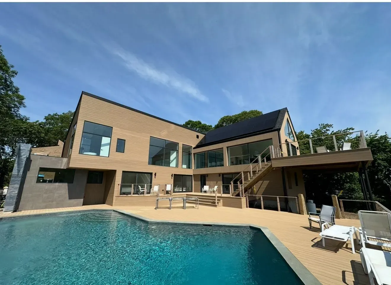 Modern house with pool and solar panels, under a blue sky.