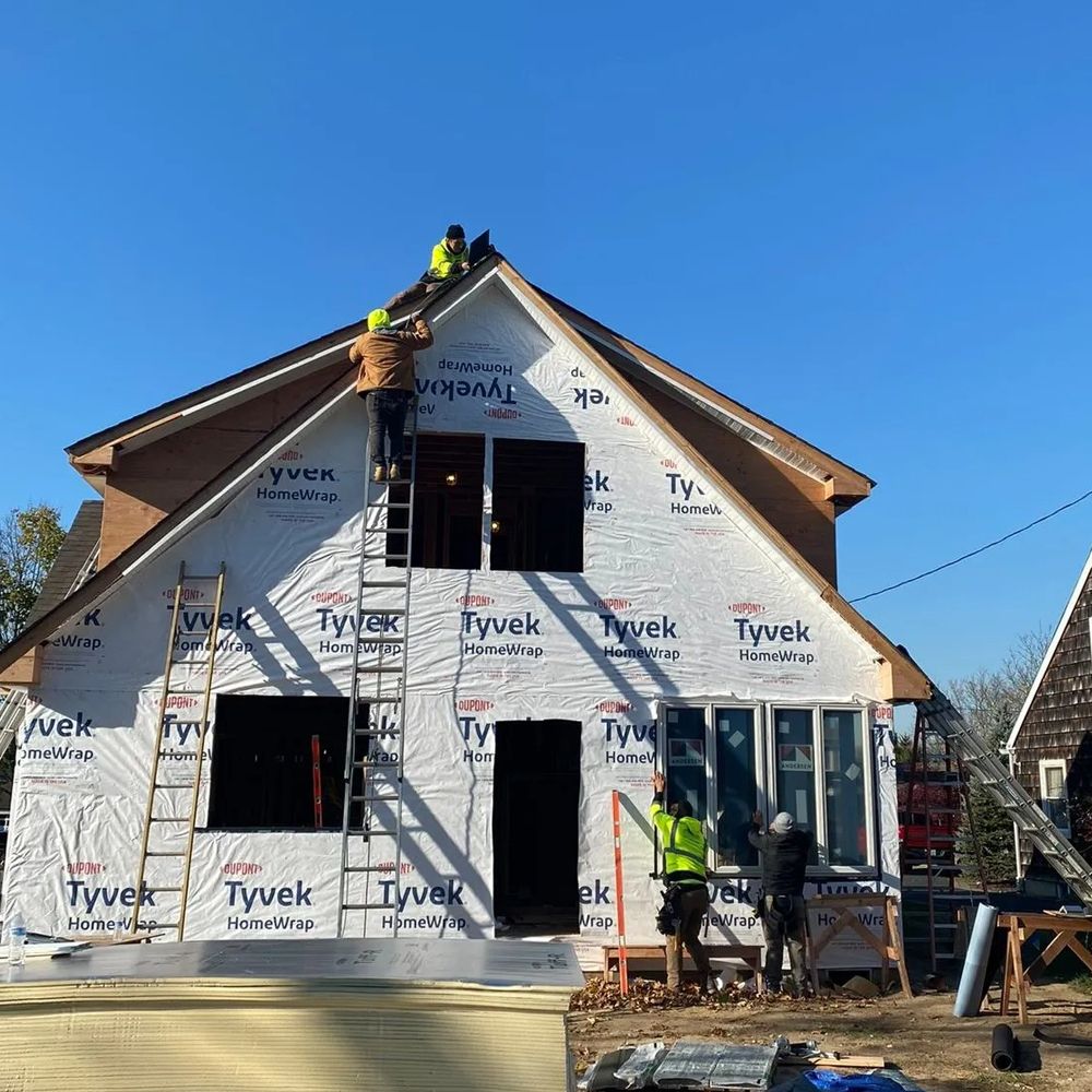 Construction workers on a house. Exterior view of a building under construction, wrapped in white Tyvek.