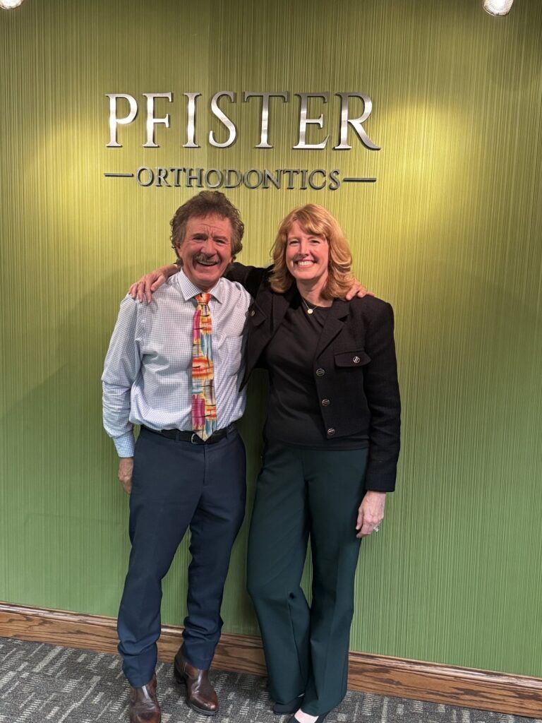 Two people standing smiling in front of a green Pfister Signatures wall