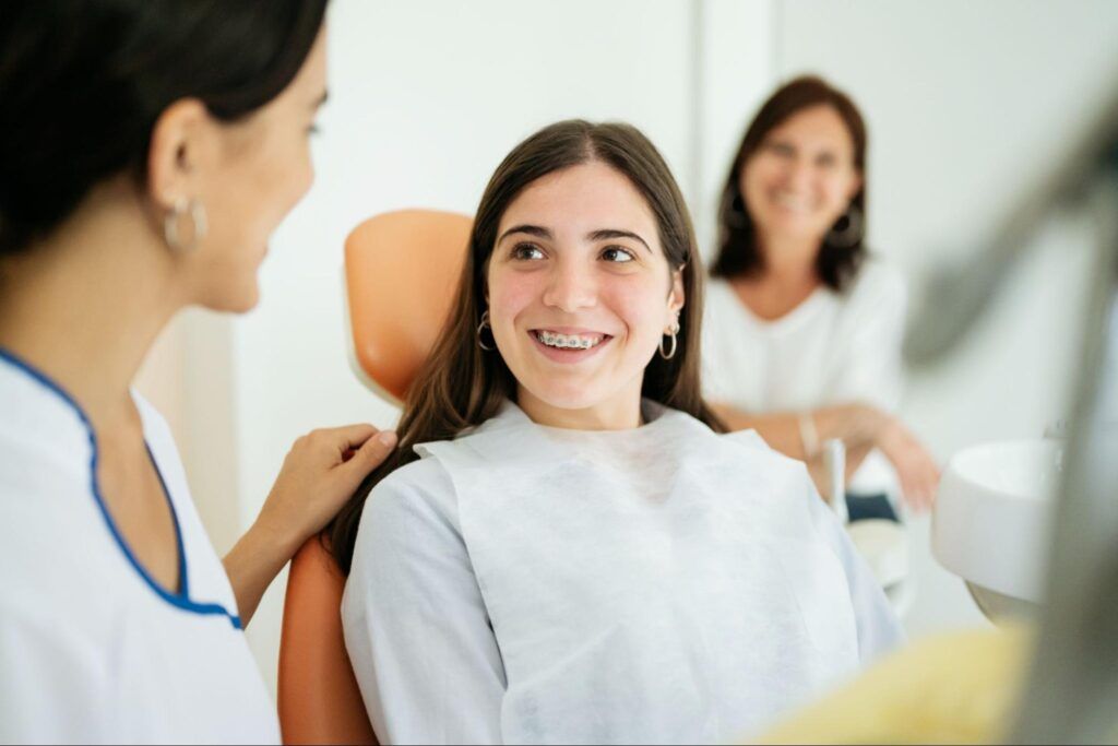 Two women talking in a bright clinic, one smiling while a clinician rests a hand on her shoulder