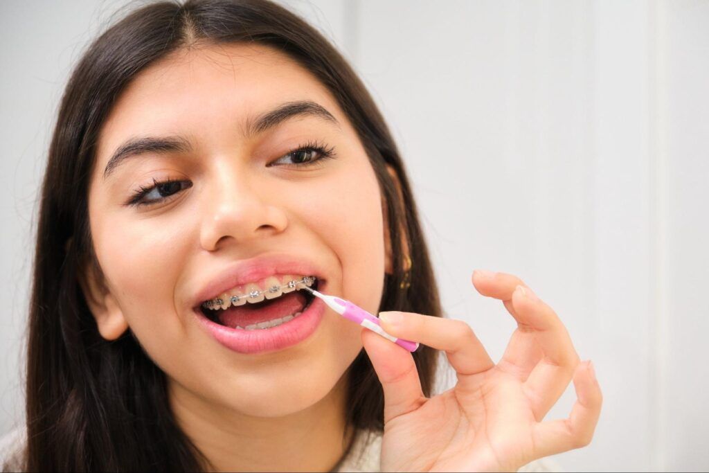 Person using pink dental floss on teeth in a bright bathroom mirror scene