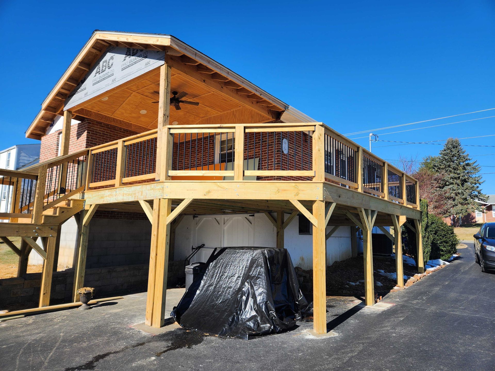 Wooden deck extension attached to a building, with a covered area. Sunny day, blue sky.