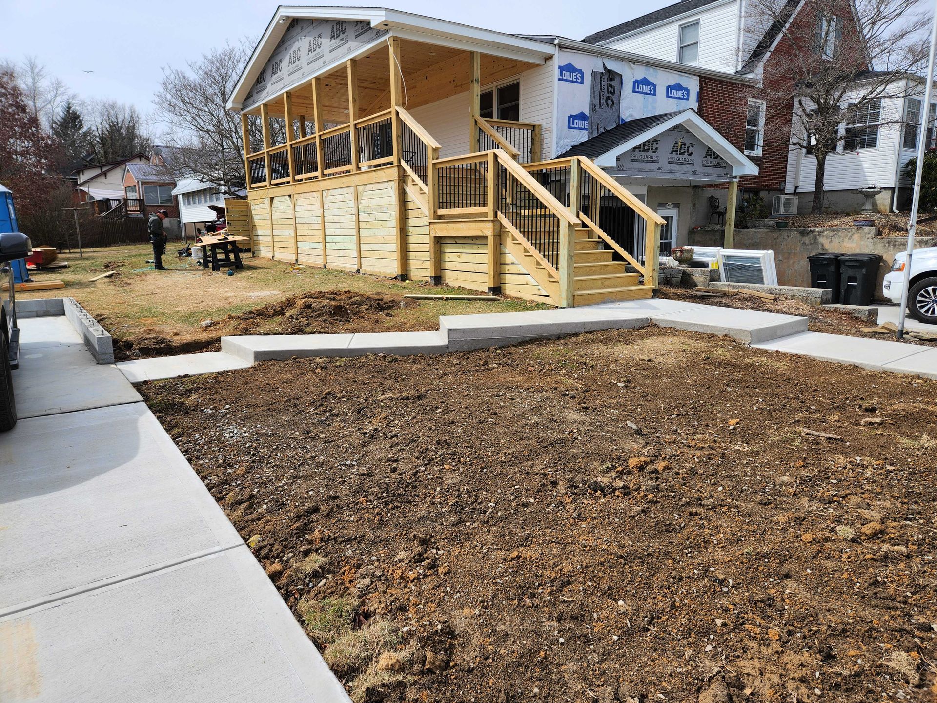 New construction house with porch, dirt lawn, and concrete pathway.
