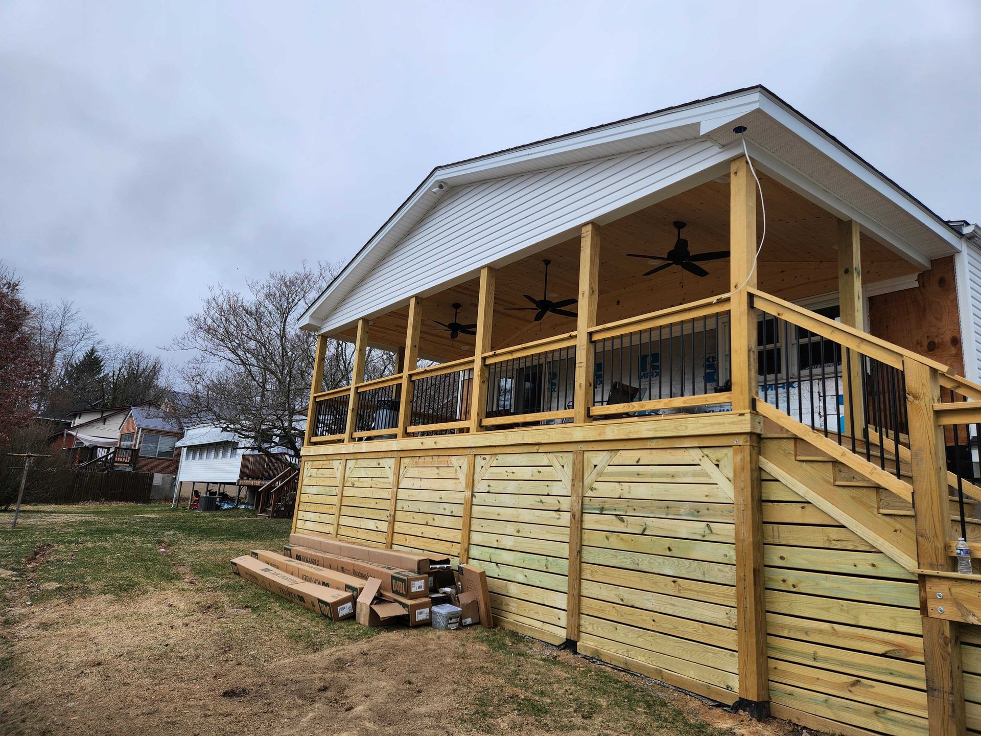 Newly built wooden deck and covered porch on a house with steps. Cloudy day.
