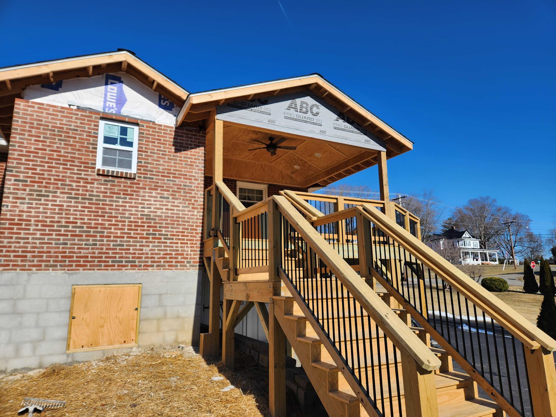 New construction home with wooden porch and stairs, brick exterior, blue sky.