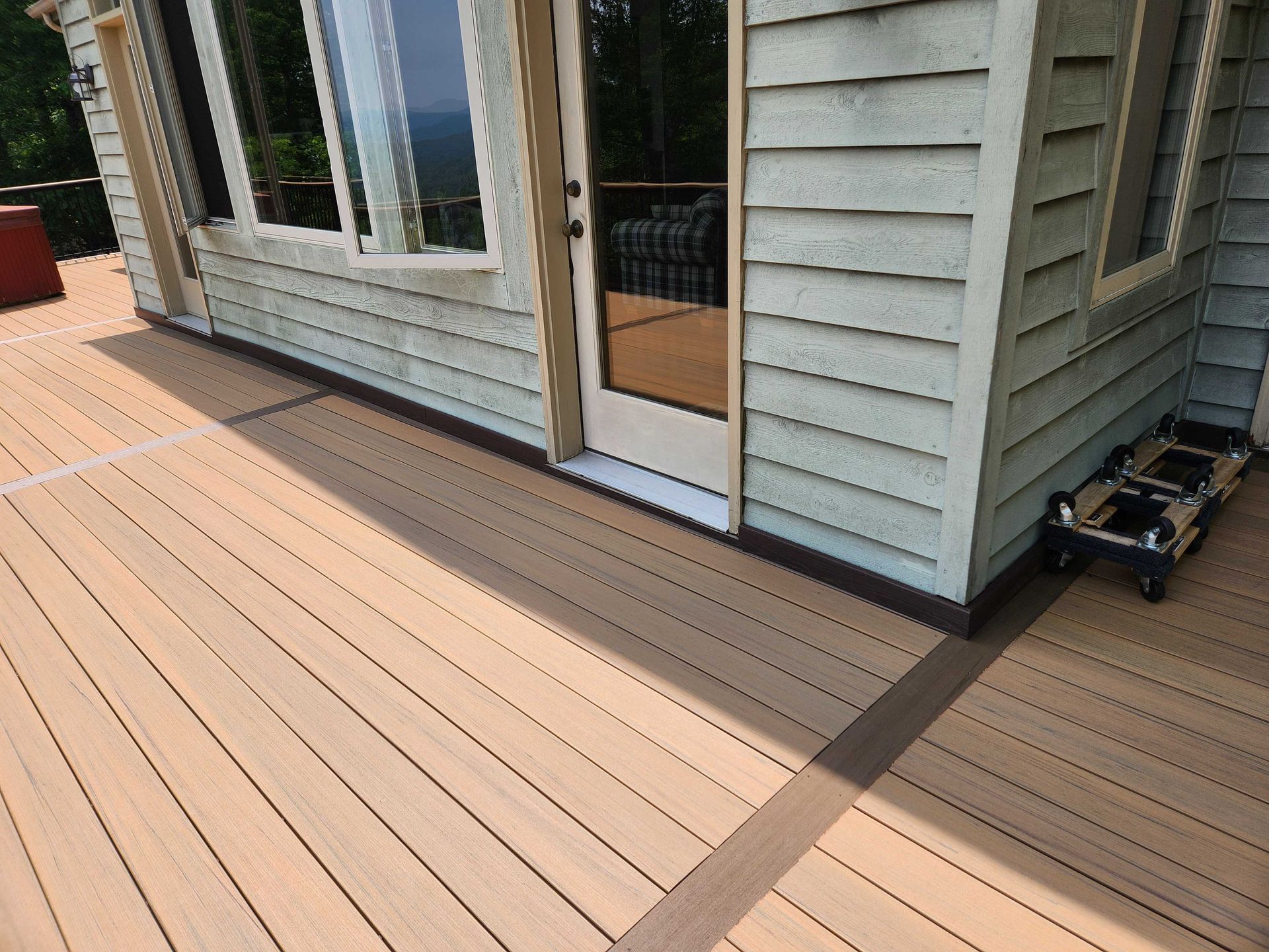 Exterior deck with composite decking, brown trim, and a door leading inside.