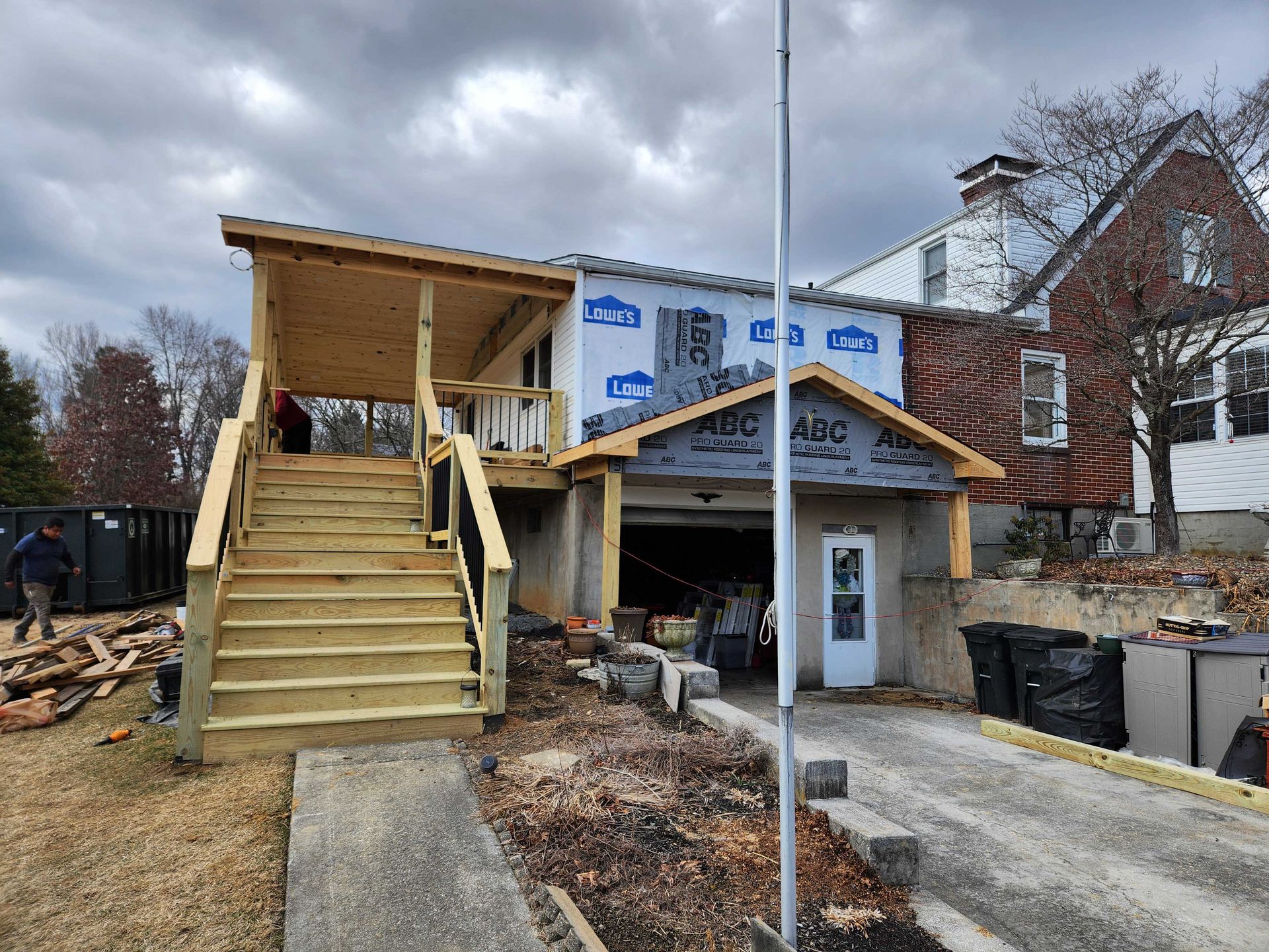 Deck with composite boards, and adjacent house with light green siding and a door.