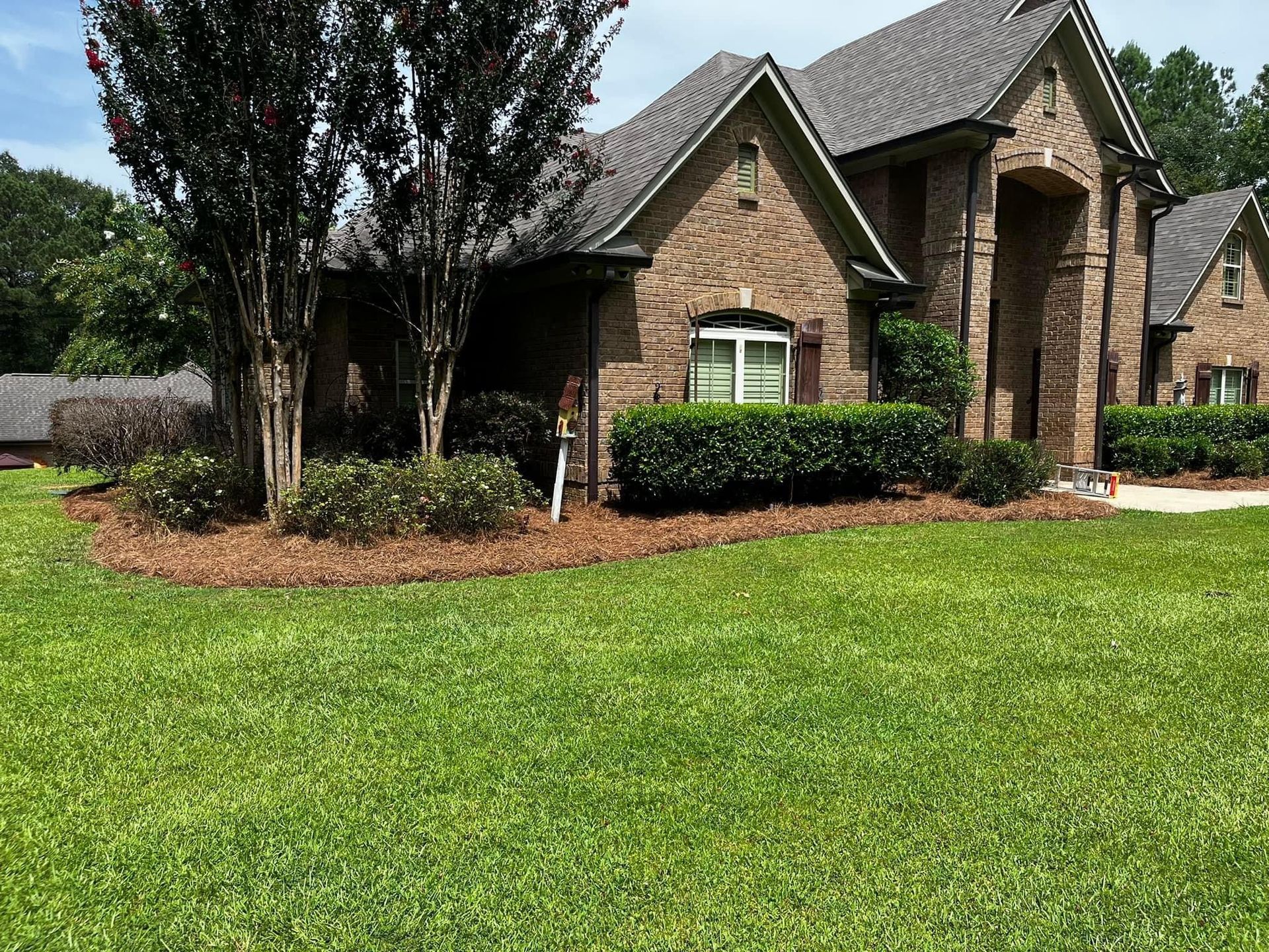 A large brick house with a lush green lawn in front of it.