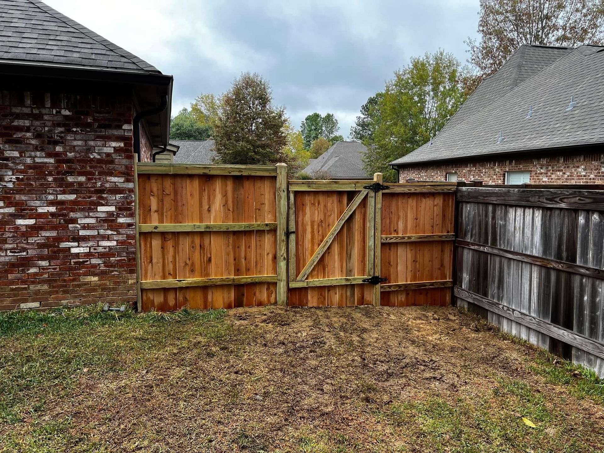 A wooden fence with a gate in the backyard of a house.