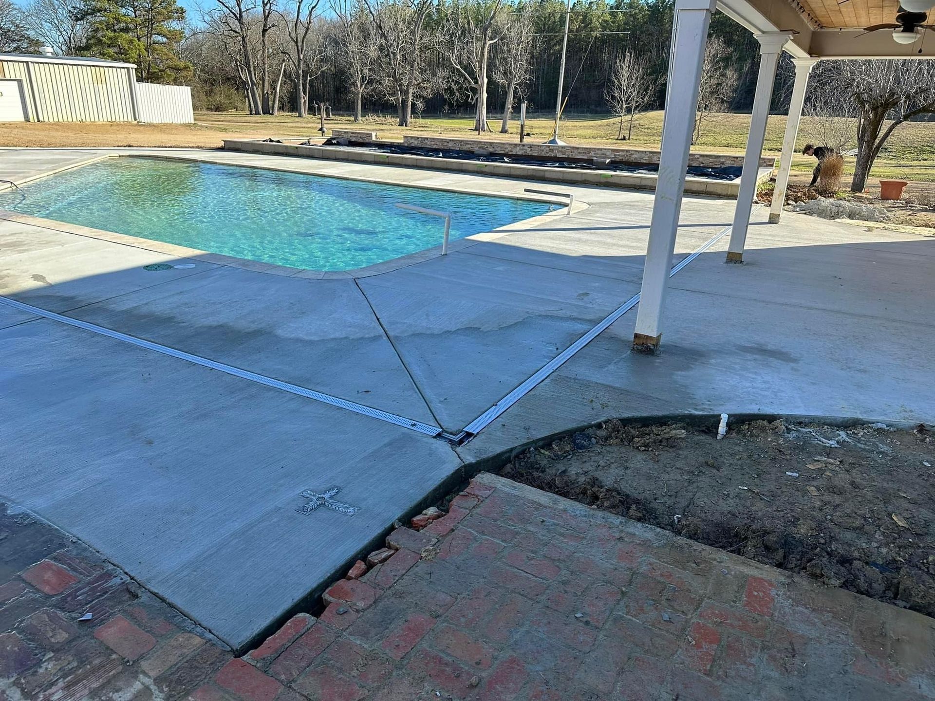 A concrete patio with a swimming pool in the background.