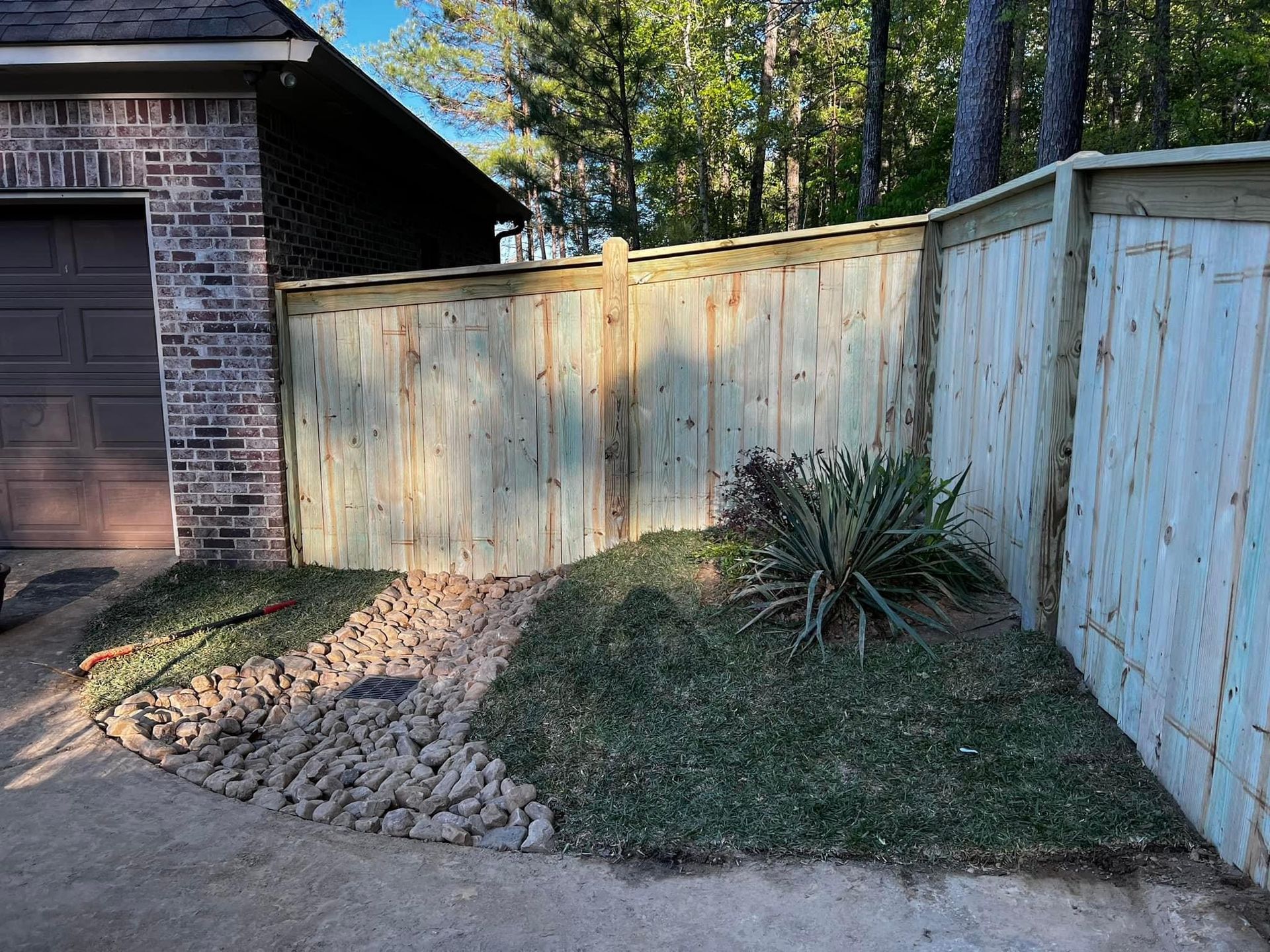 A wooden fence is in front of a brick house.