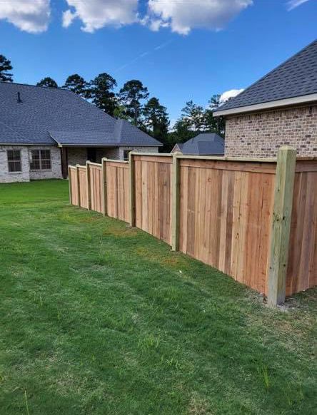 A wooden fence is in the backyard of a house.