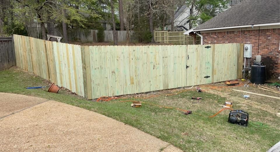 A wooden fence is being built in the backyard of a house.