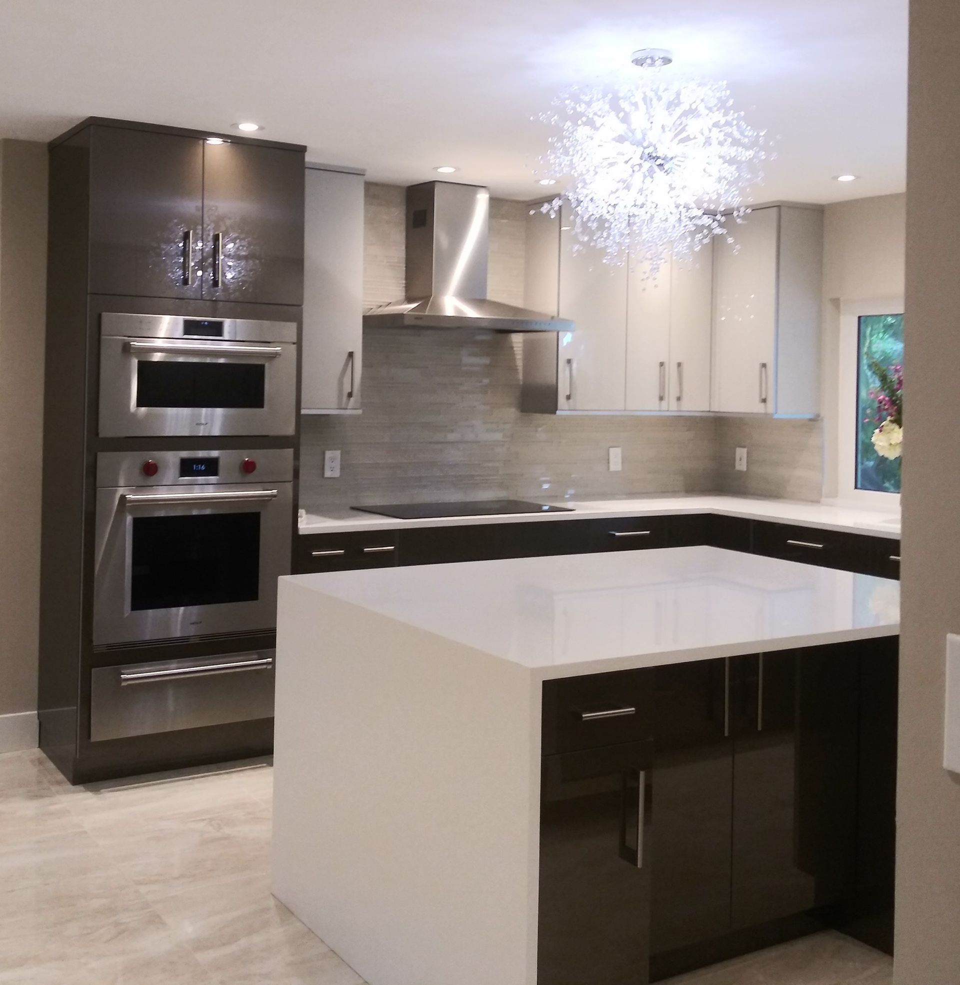 Modern kitchen with white countertops, dark cabinetry, stainless steel appliances, and a central island.