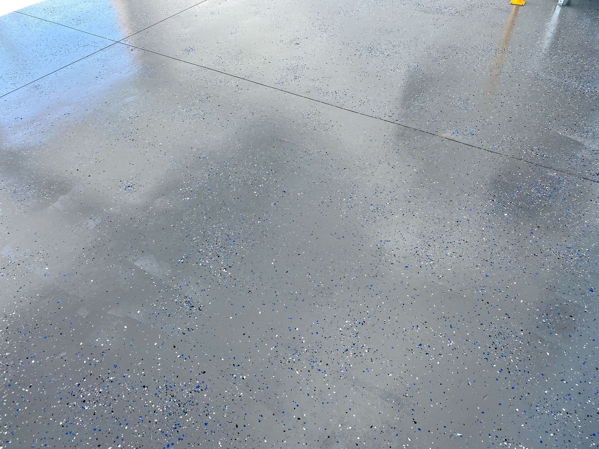 Speckled gray concrete floor with a diagonal seam and a small yellow object at the top right