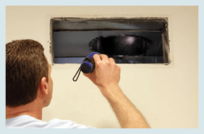 A man inspecting the air duct using flashlight