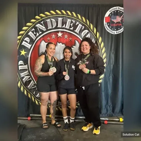 Three people with medals pose in front of a 