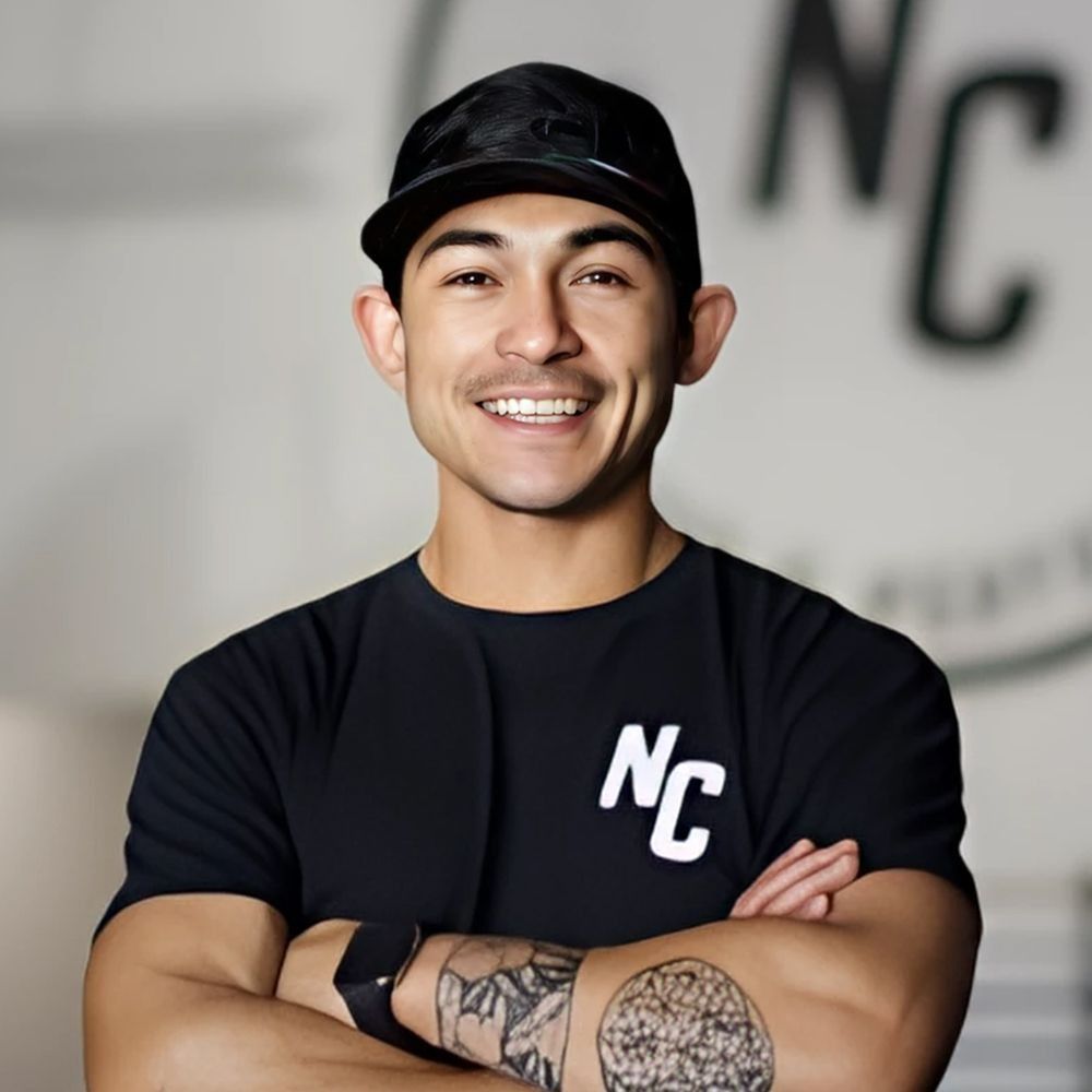 Man with arms crossed, wearing a black cap and shirt with 