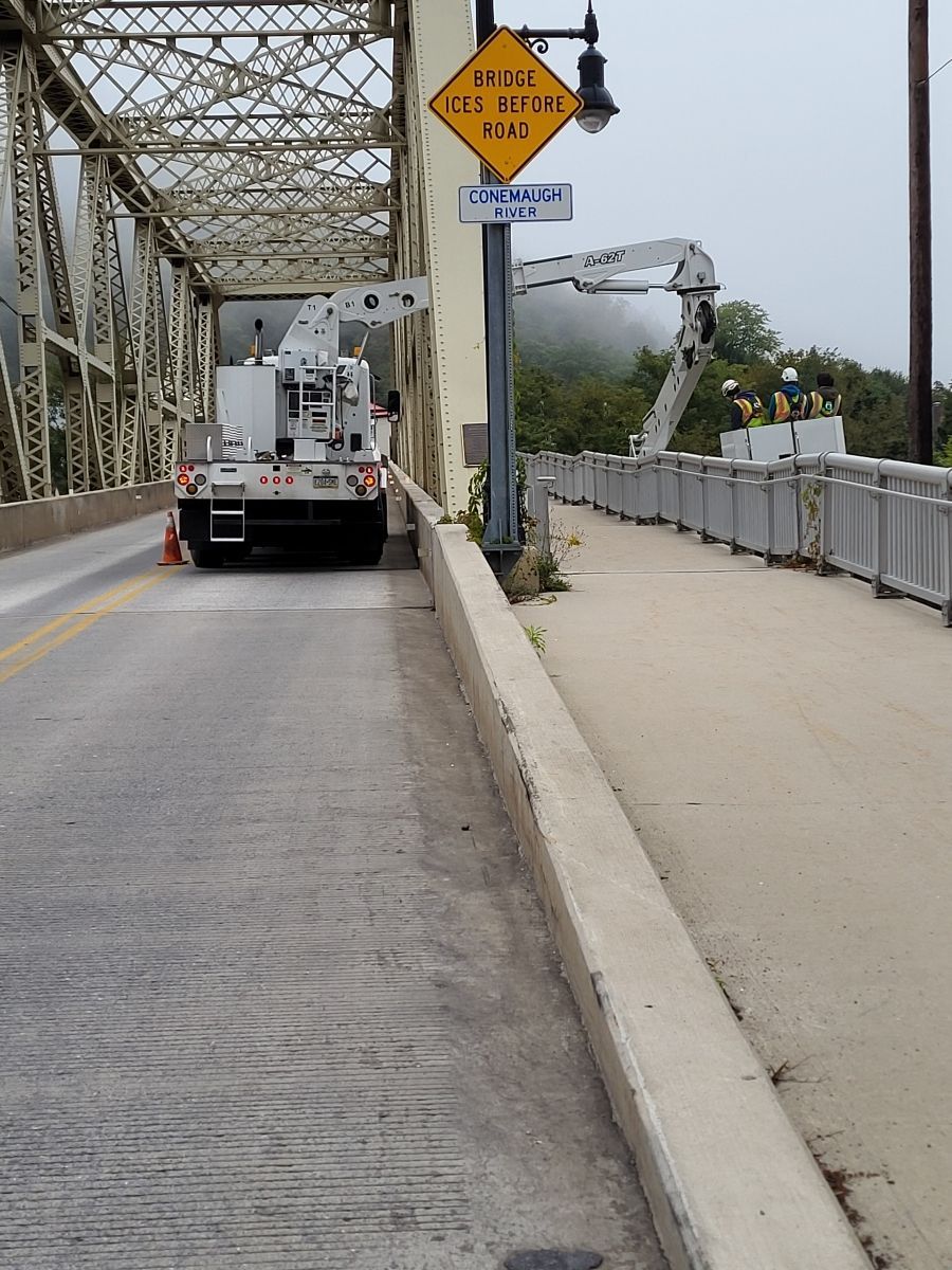A yellow sign on the side of a bridge says do not walk