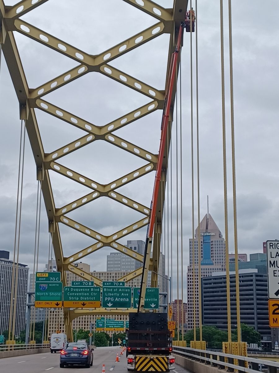 A truck is driving under a bridge with a sign that says no left turns