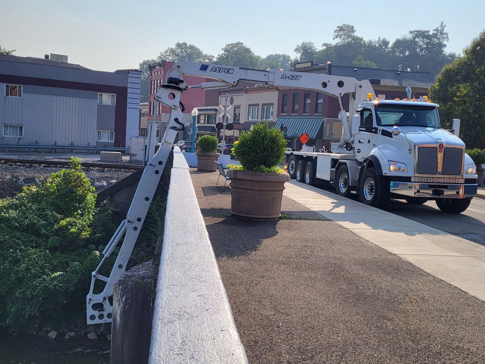 A white truck with a crane on the back is parked on the side of the road