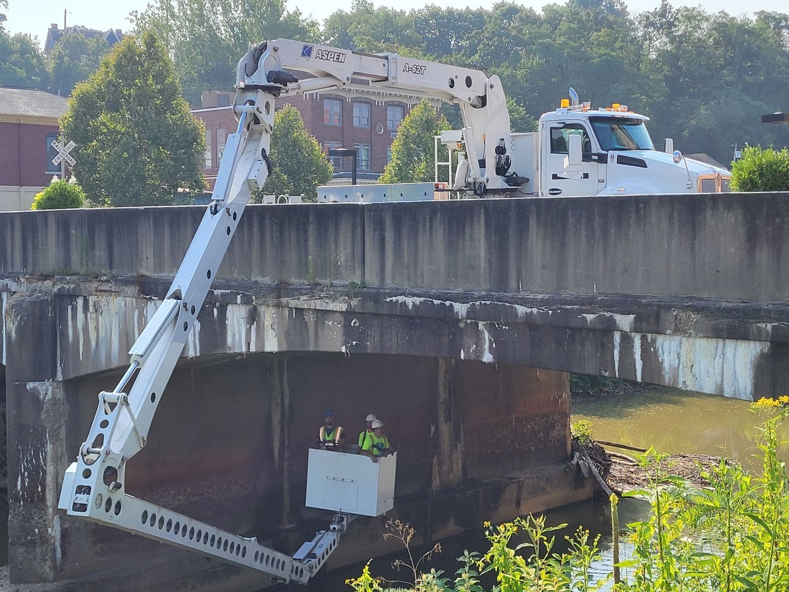 A white truck is driving over a bridge with a crane attached to it