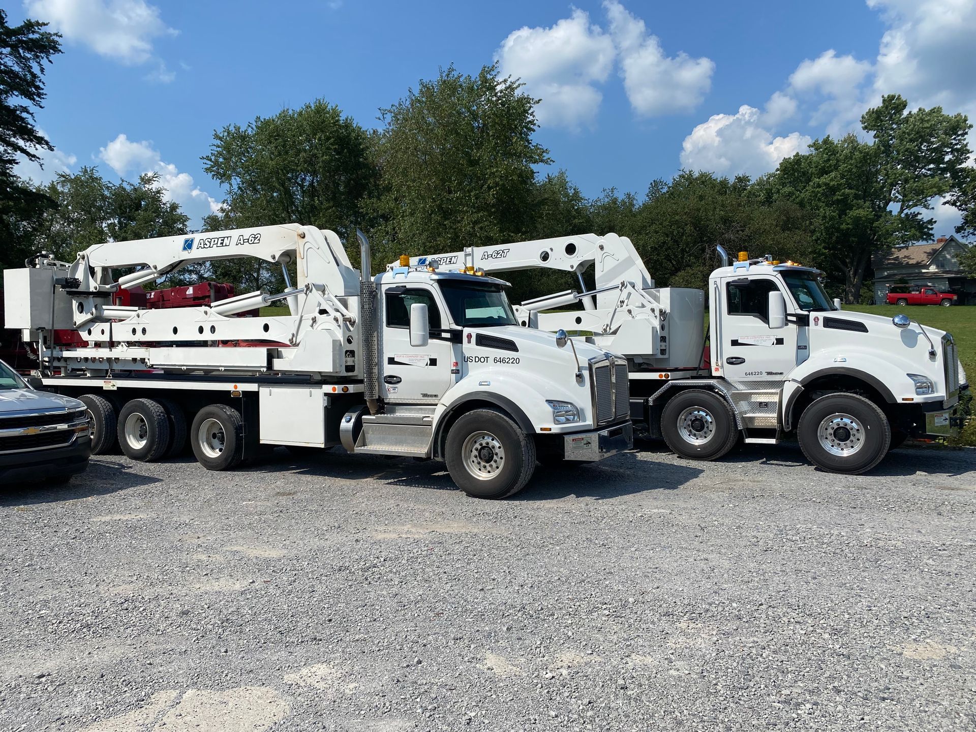 Two trucks are parked next to each other in a gravel lot