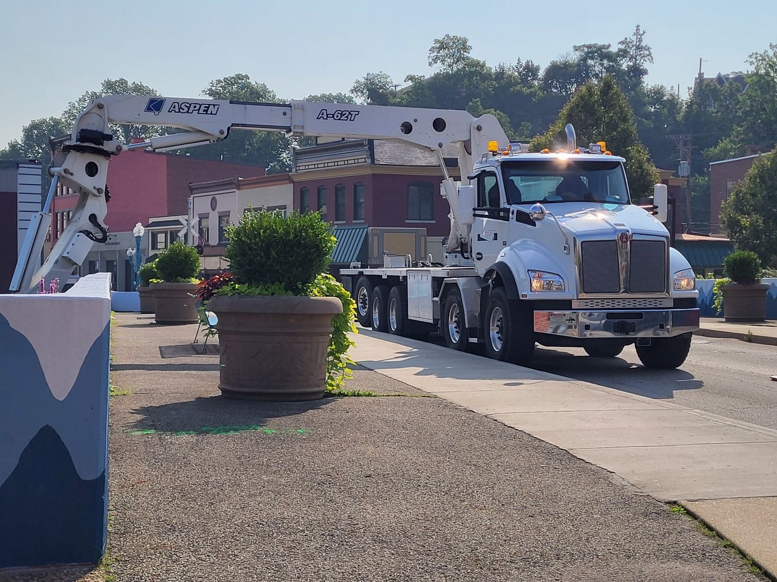 A white truck with a crane on the back is driving down a street
