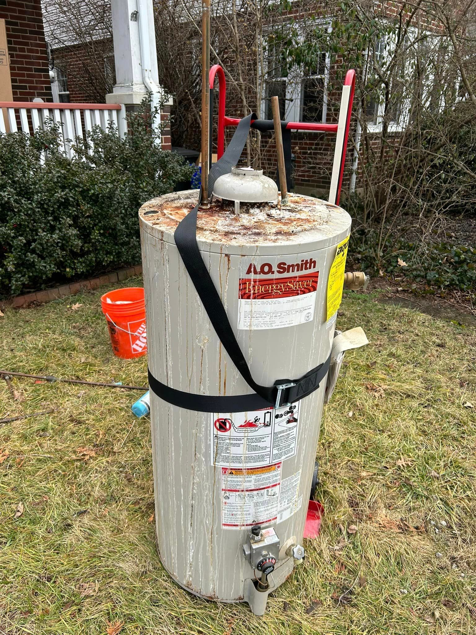 a water heater is sitting in the grass in front of a house .