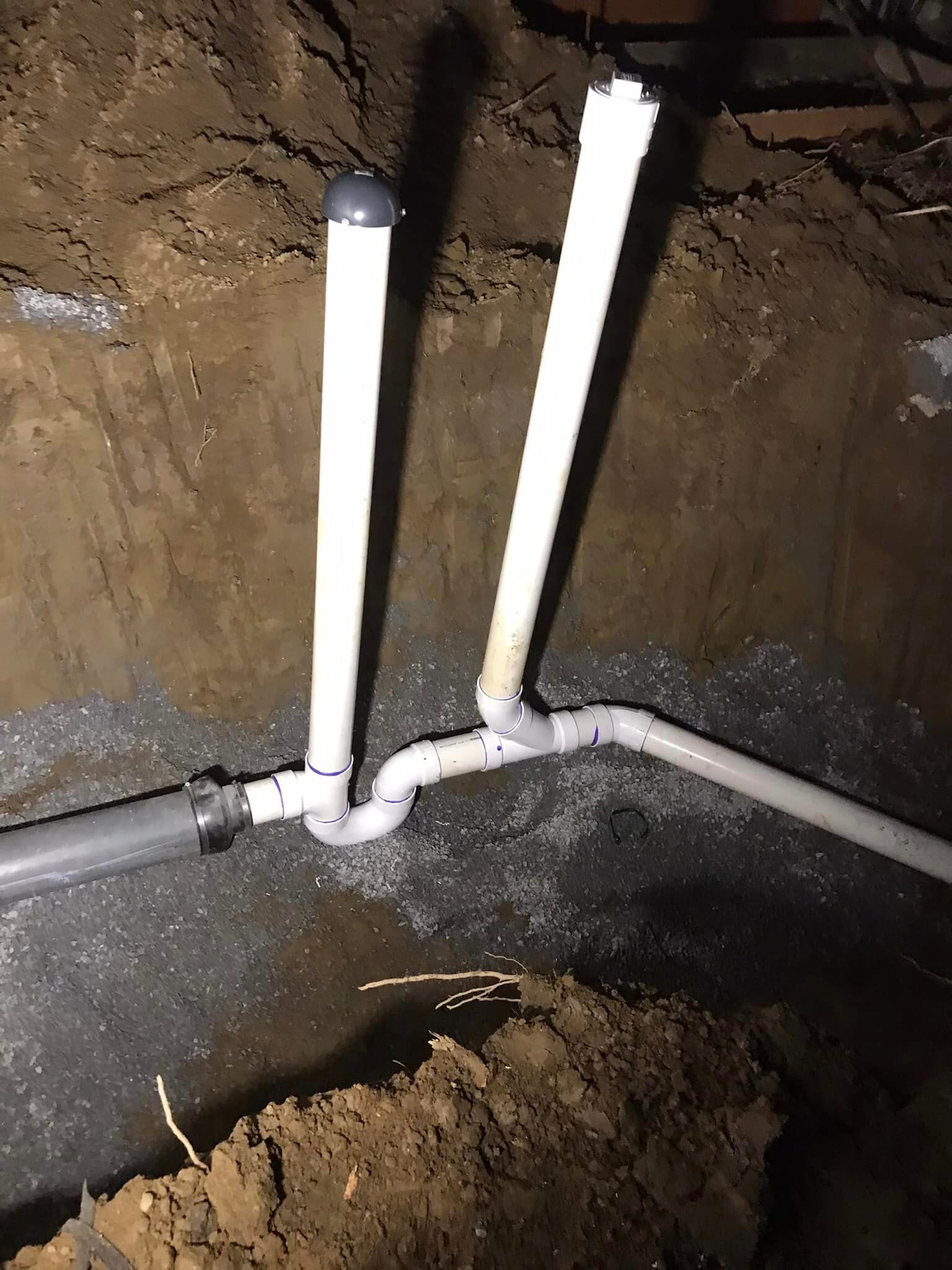 a couple of pipes are connected to each other in a hole in the ground .