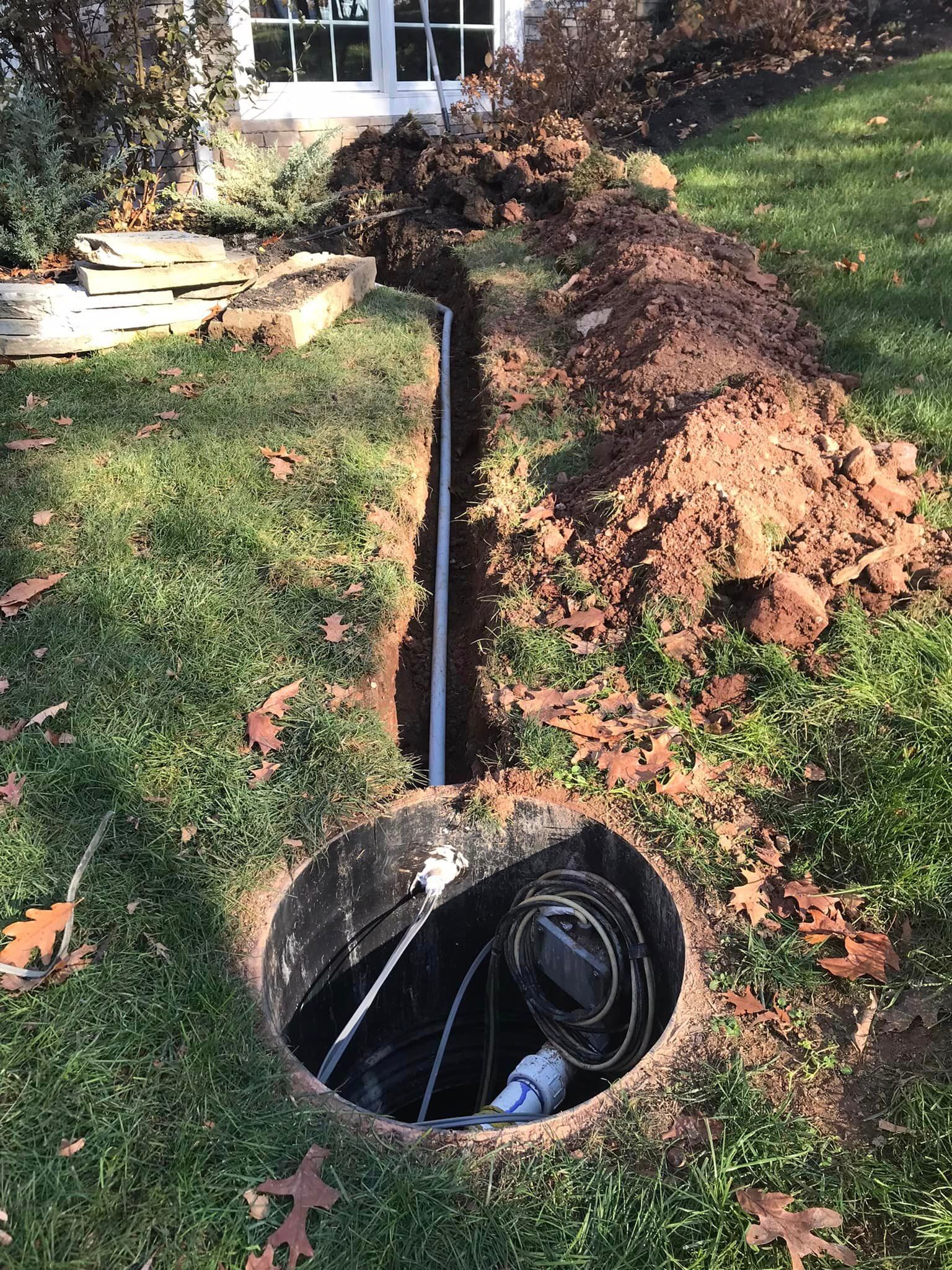 a hole in the ground in a yard with a pipe coming out of it .