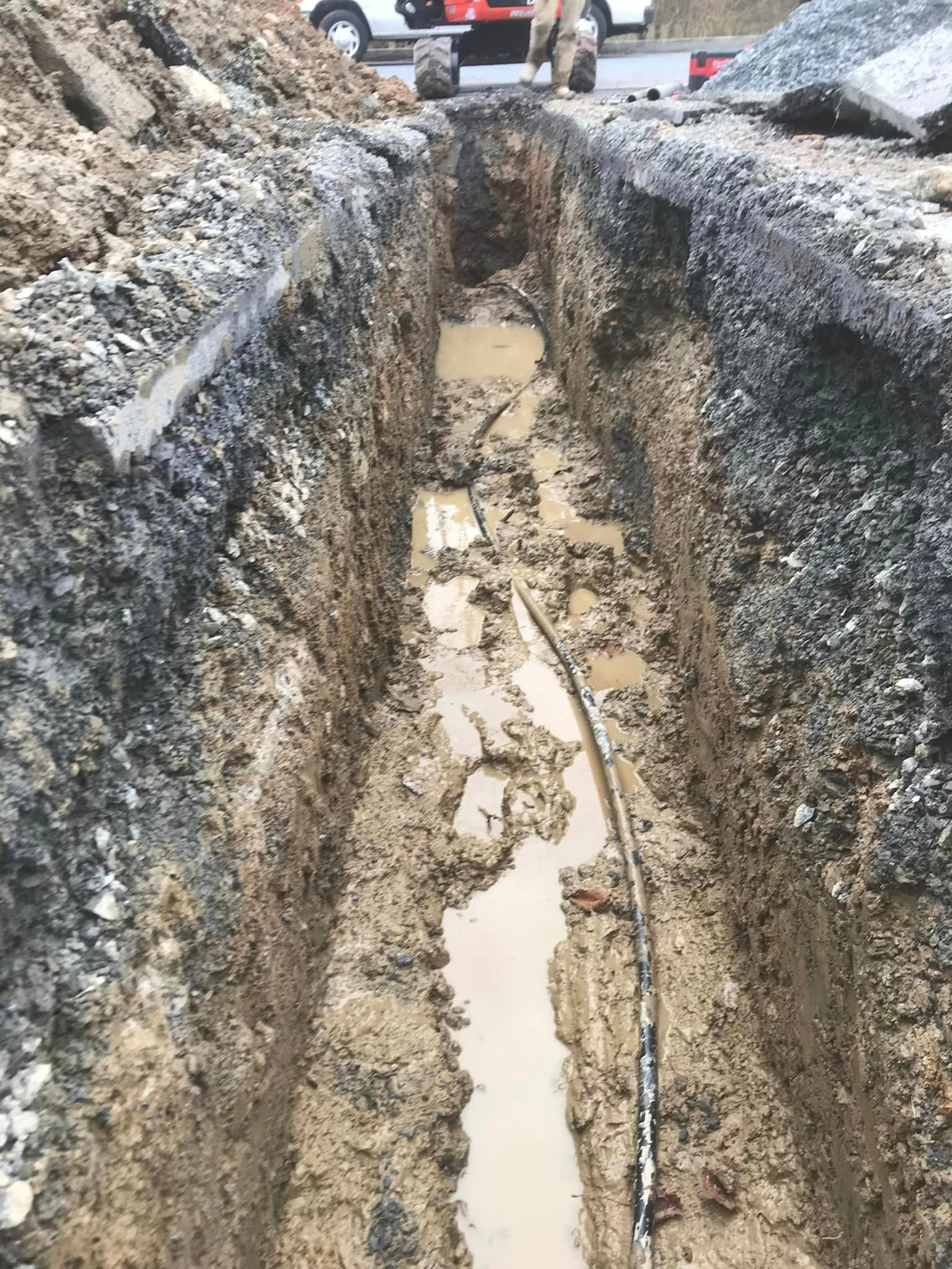 a muddy trench with a hose coming out of it .